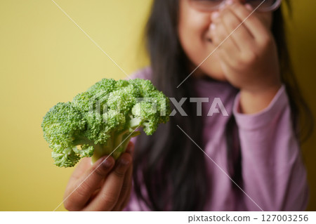 Child holds broccoli while laughing in the kitchen Child holds broccoli while laughing in the kitchen 127003256