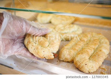 Delicious pastry being picked up in a bakery 127003345