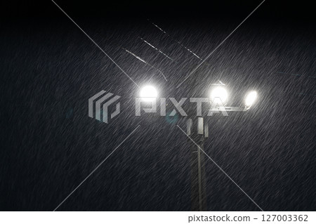 Illumination of heavy rain at night: Raindrops illuminated by street lights Illumination of heavy rain at night: Raindrops illuminated by street lights 127003362