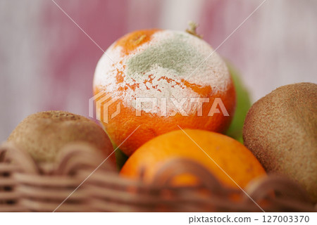 Moldy fruit in a basket spoiling fresh produce display 127003370
