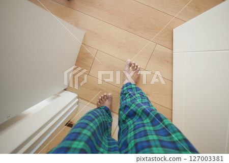 Walking barefoot on wooden floor in cozy pajamas Walking barefoot on wooden floor in cozy pajamas 127003381