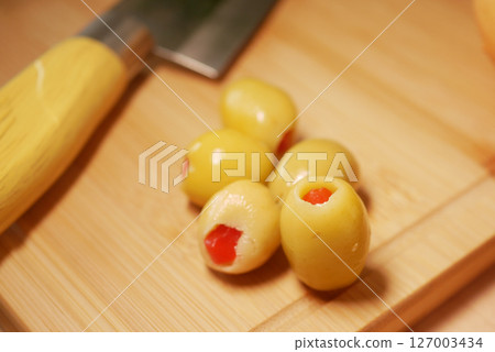 Stuffed olives on a wooden cutting board with knife 127003434