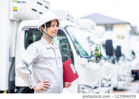 一名身穿工作服的年輕人站在一輛卡車前 127004039