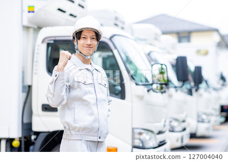 一名身穿工作服的年輕人站在一輛卡車前 127004040