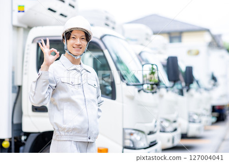 一名身穿工作服的年輕人站在一輛卡車前 127004041