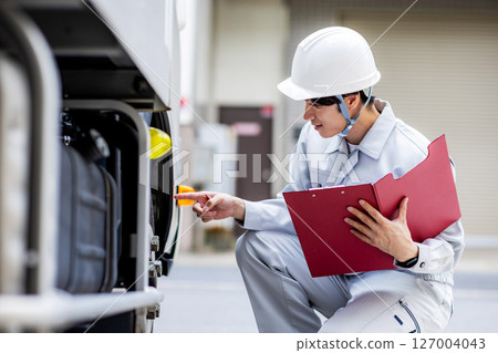 一名身穿工作服的年輕人站在一輛卡車前 127004043