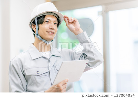 A young man in work clothes holding a tablet 127004054
