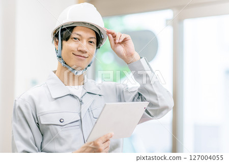 一名身穿工作服的年輕人手持平板電腦 一名身穿工作服的年輕人手持平板電腦 127004055
