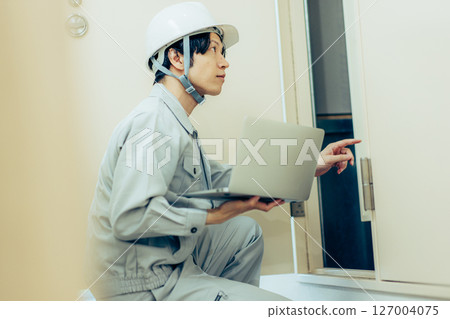 Man in work clothes holding a laptop Man in work clothes holding a laptop 127004075