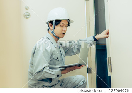 Man in work clothes holding a laptop Man in work clothes holding a laptop 127004076