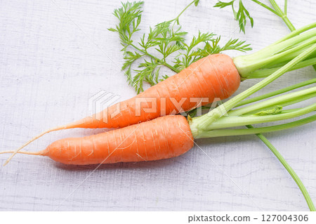 Organic mini carrots with leaves isolated on white wood background. 127004306