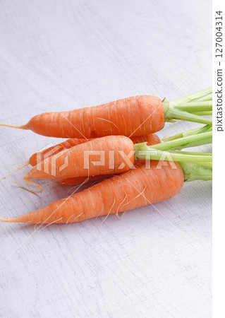 Organic mini carrots with leaves isolated on white wood background. 127004314