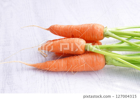 Organic mini carrots with leaves isolated on white wood background. 127004315