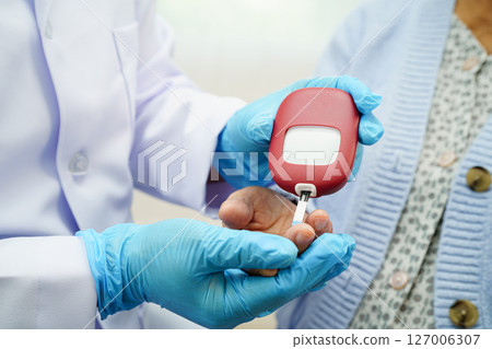 Asian doctor using digital glucose meter for check sample blood sugar level to treatment diabetes. 127006307