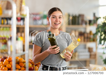 European youth girl choose and buy vegetable oil in store 127006700