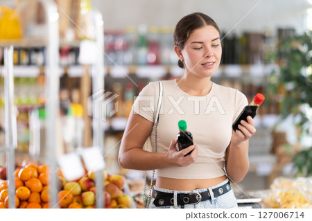 European smiling girl hold bottle, choose and buy soy sauce in store 127006714