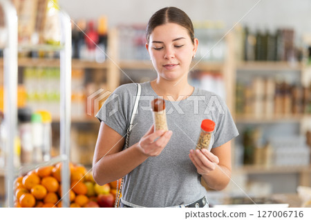 Young woman choosing seasoning herbs in grocery 127006716