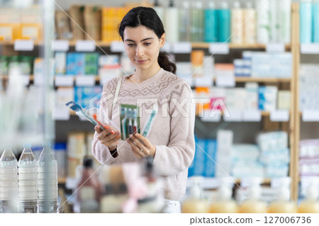 Young european woman chooses a toothbrush Young european woman chooses a toothbrush 127006736