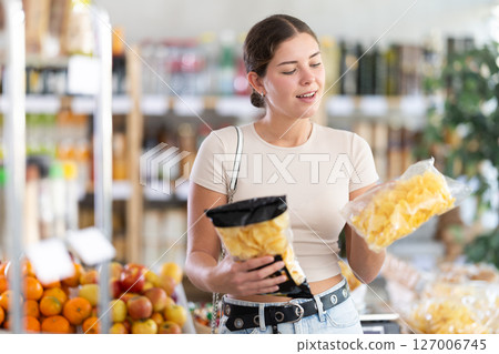 Young woman choosing chips in grocery store 127006745