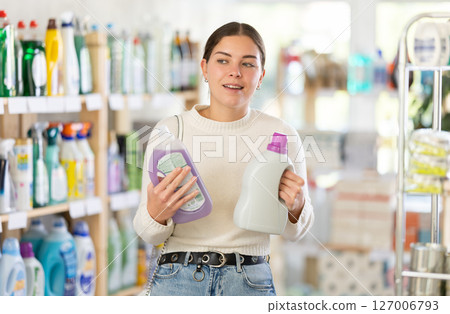 Girl housewife in household store examines package, chooses liquid detergent 127006793