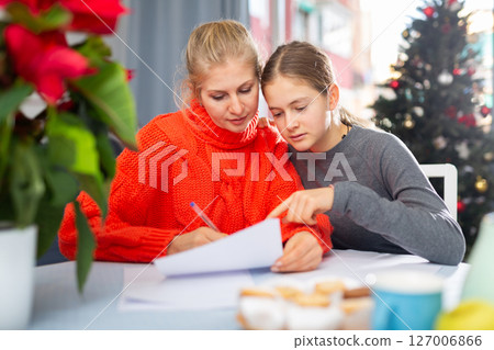 Woman and her daughter writing list of Christmas presents Woman and her daughter writing list of Christmas presents 127006866