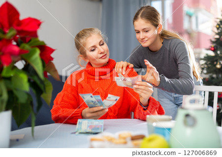 Mother giving teenage daughter money to celebrate christmas and new year 127006869