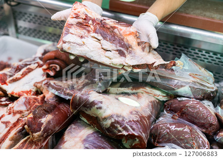 Close-up sellers hands hold put add T-bone steak to glass showcase refrigerator display Close-up sellers hands hold put add T-bone steak to glass showcase refrigerator display 127006883