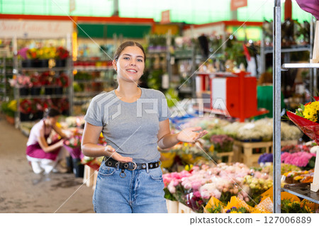 Young woman customer standing against the background of various flowers 127006889