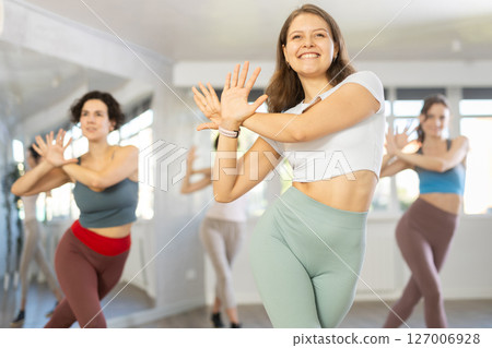 Cheerful young female instructor leading Zumba class for women 127006928