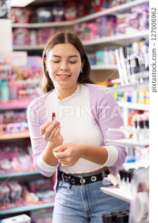 Young female customer searching for reliable lipstick in cosmetics shop Young female customer searching for reliable lipstick in cosmetics shop 127006962