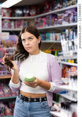 Beautiful european woman buying shampoo or hair care products in supermarket Beautiful european woman buying shampoo or hair care products in supermarket 127006985