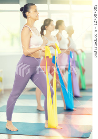 Young woman exercising with pilates band 127007005