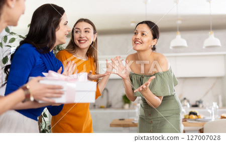 Three women have arrived for birthday celebration and presenting gift to birthday woman 127007028