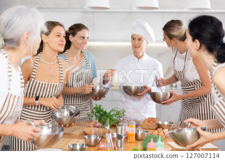 Young woman holding bowl and talking to other members Young woman holding bowl and talking to other members 127007114