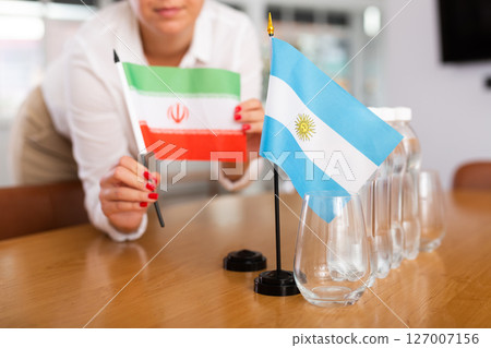 Employee of delegation prepares negotiating table - sets up flag of Argentina and Iran 127007156