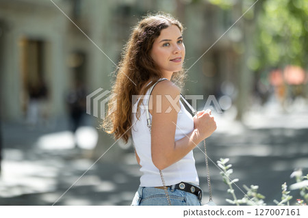 Cheerful girl walking at the street among architecture with bag Cheerful girl walking at the street among architecture with bag 127007161