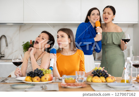 Group of female friends are having fun singing karaoke during feast and gatherings. Group of female friends are having fun singing karaoke during feast and gatherings. 127007162