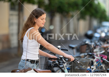 Girl standing with bicycle ready to start riding around city Girl standing with bicycle ready to start riding around city 127007244