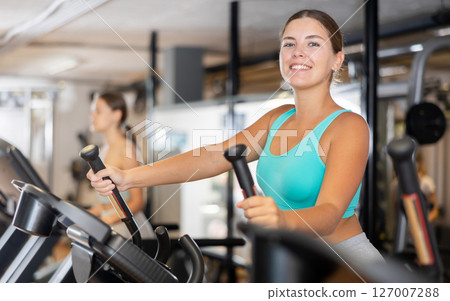 Young woman working out on elliptical machine Young woman working out on elliptical machine 127007288