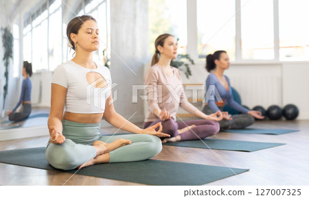 Young girls making yoga meditation in lotus pose in fitness studio 127007325