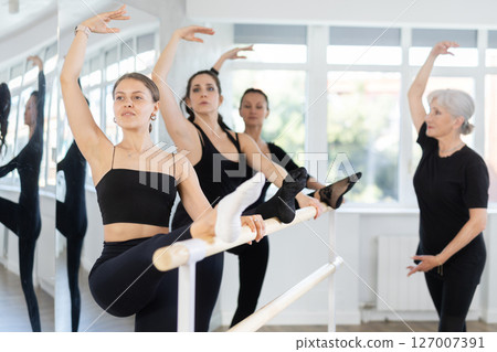 Students of dance studio perform exercises under supervision of mature female coach. 127007391