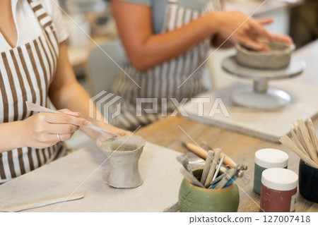 Unrecognizable two young women pottery workshop workers sculpt from raw clay Unrecognizable two young women pottery workshop workers sculpt from raw clay 127007418