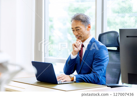 Middle-aged businessman using a computer Middle-aged businessman using a computer 127007436