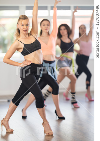 Female instructor performing graceful sass dance movements during group class Female instructor performing graceful sass dance movements during group class 127007496