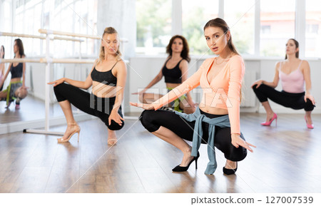 Confident woman leading group heels dance class in studio 127007539