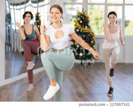 Young woman energizing female group during dance workout in Christmas studio 127007581