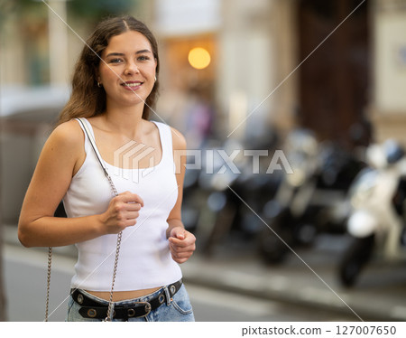 Young smiling girl walks along city street 127007650