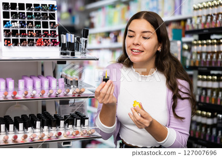 Woman shopping in cosmetics store, choosing new nail polishes 127007696