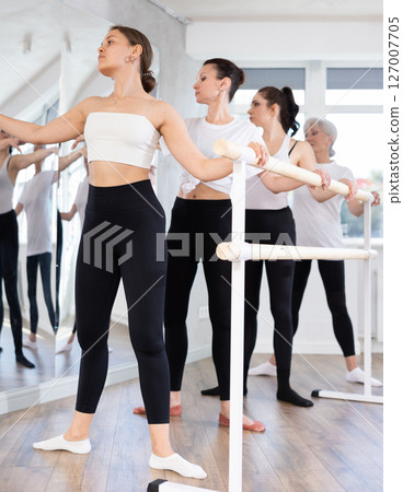 Graceful women of different ages practice at ballet stand in fifth position Graceful women of different ages practice at ballet stand in fifth position 127007705
