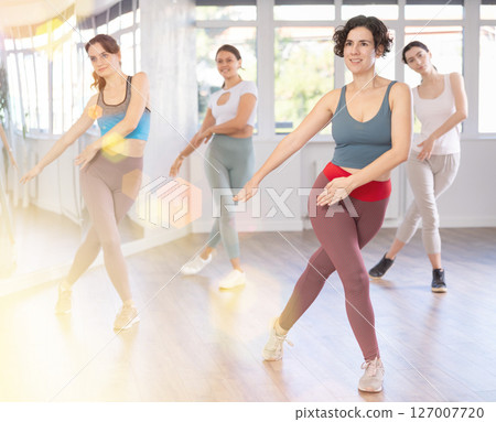 Smiling Hispanic woman enjoying vigorous dance at group class 127007720